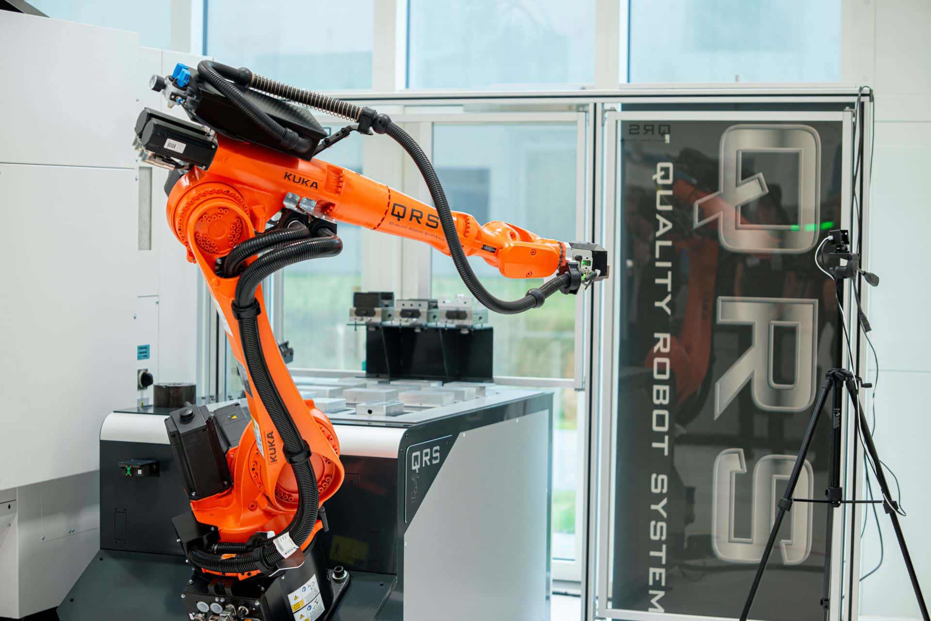 Kuka-robot KR20 der er del af en Smartzell M20 med et qrs banner og hegn i lexan i baggrunden