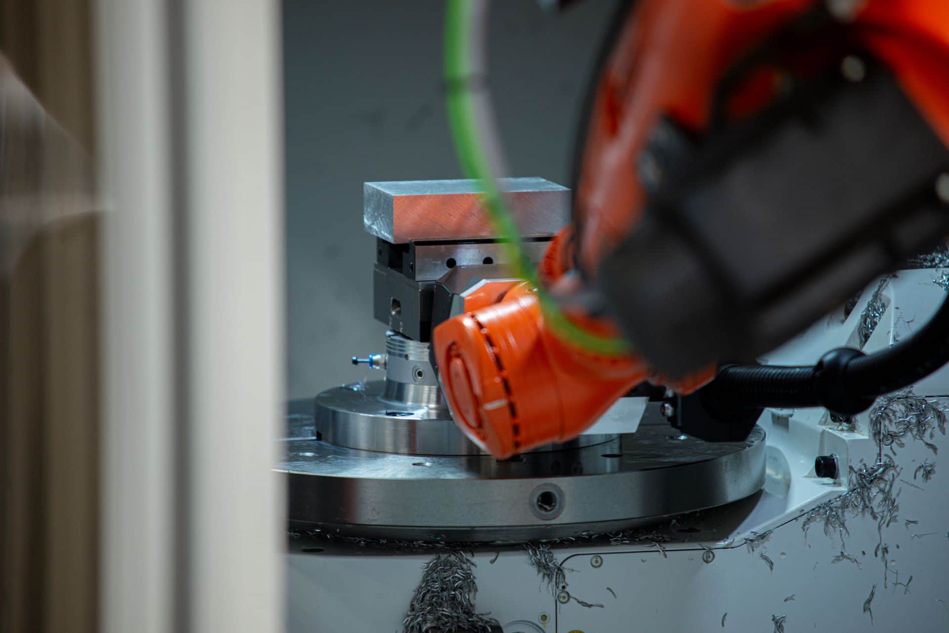 Kuka-robot placerer et råemne fastspændt i en skruestik i en cnc-maskine