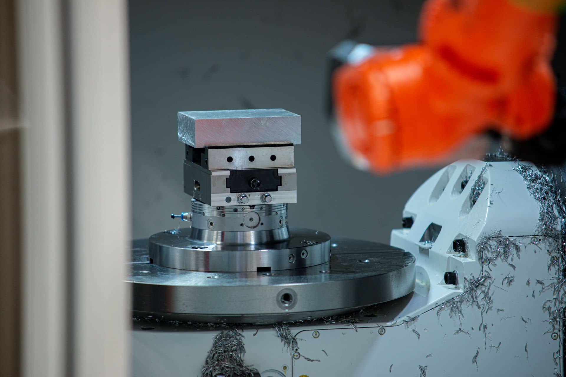 Kuka-robot har placeret et råemne fastspændt i en skruestik i en cnc-maskine og er på vej ud